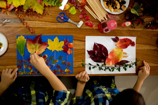 istock Children, applying leaves using glue, scissors, and paint, while doing arts and crafts in school 1174236766