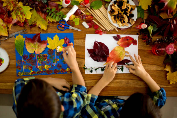 istock Children, applying leaves using glue, scissors, and paint, while doing arts and crafts in school 1174236805