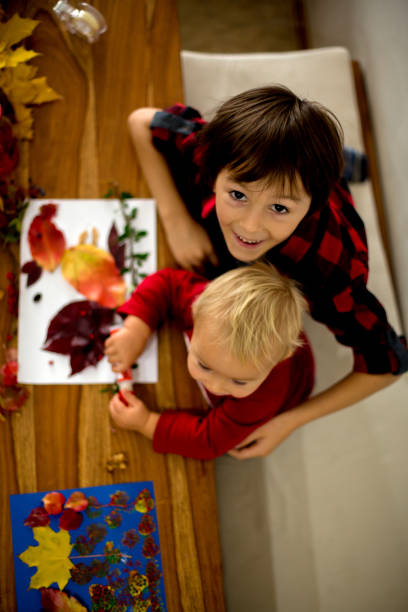 istock Children, applying leaves using glue, scissors, and paint, while doing arts and crafts in school 1174236862