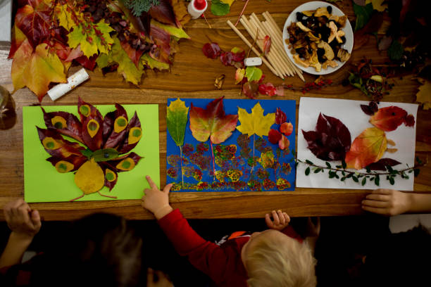 istock Children, applying leaves using glue, scissors, and paint, while doing arts and crafts in school 1174236901
