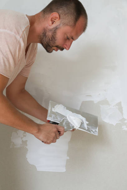 istock Man plastering wall with putty-knife. Fixing wall surface and preparation for painting. DIY housing improvement project. 1174238367