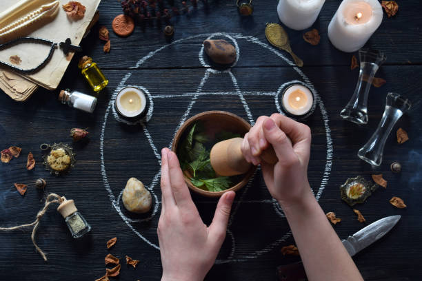 les mains de femmes font la potion d'amour sur le cercle de pentagramme avec des bougies, des pierres et de vieux livres sur la table de sorcière. concept occulte, ésotérique ou divination. mystique, halloween et fond de cru - wicca photos et images de collection