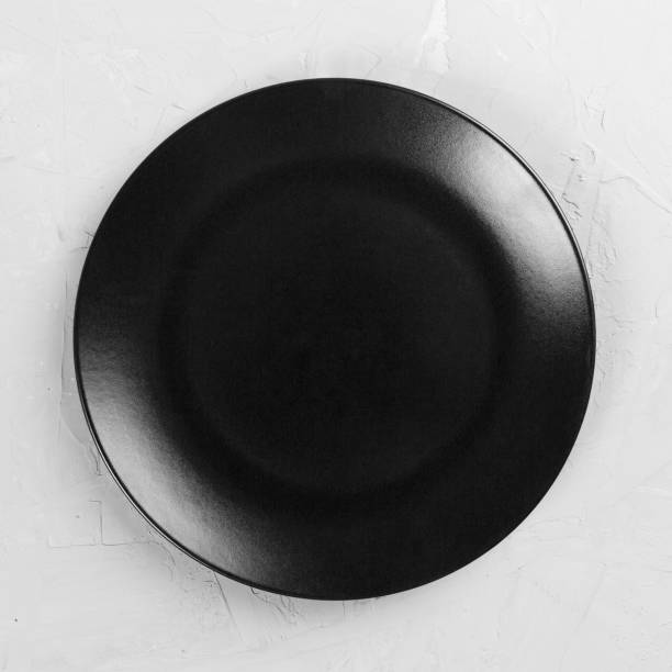 Black round plate on wooden background, top view, copy space