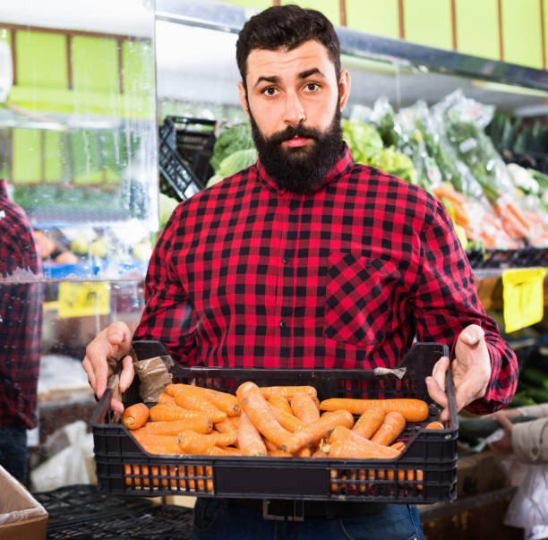 Young male seller offering carrots