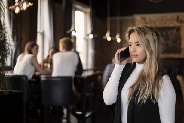 istock Serious young woman talking on her phone in a bar 1174243731