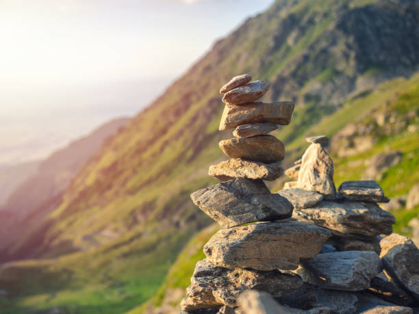 stone stack with balanced stones on blurred mountain background in sunset warm light - stacking stone rock full imagens e fotografias de stock