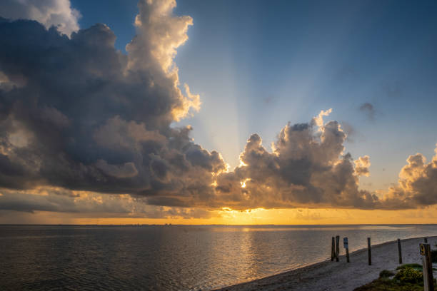 Dramatic sky at sunrise over water with reflection and sunray
