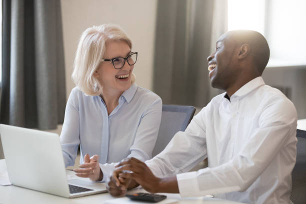 istock Smiling diverse colleagues laugh cooperating at laptop in office 1174254686