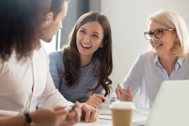 istock Diverse employees laugh talking sitting at desk in office 1174254824
