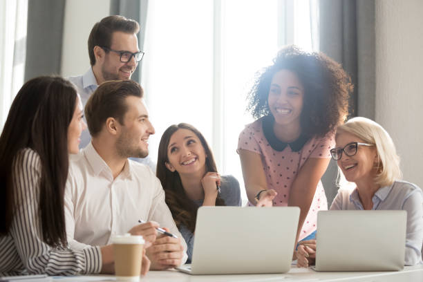 istock Smiling diverse employees laugh working together at laptop in office 1174254829