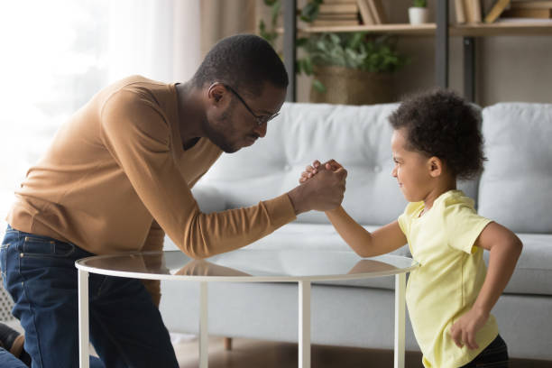 istock Black dad and little son have fun arm wrestling 1174255190