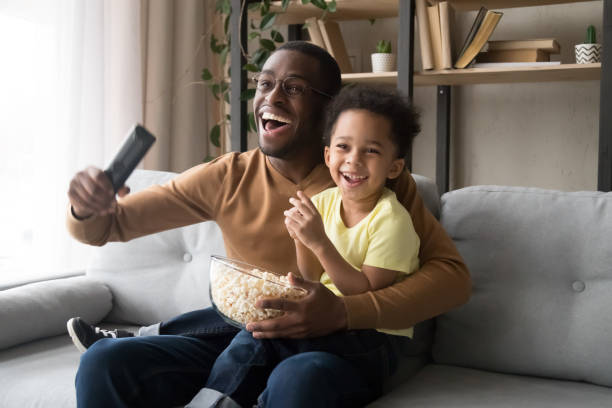 istock Excited black dad and son cheering watching match on TV 1174255197