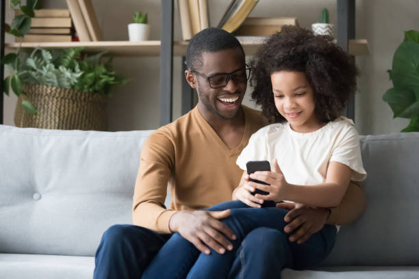 istock Happy black dad hug daughter using smartphone together 1174255234