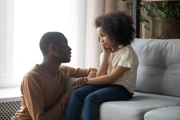 Supportive black dad talk cheering sad preschooler daughter Loving african American father talk with upset preschooler daughter helping with problem, caring black young dad speak with sad girl child holding caressing hand, show support and understanding one parent stock pictures, royalty-free photos & images