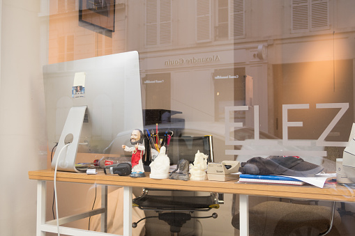 Paris, France - Aug 30, 2019: Apple Imac on table emty office workplace, seen from the street in 7th arrondissement of Paris.