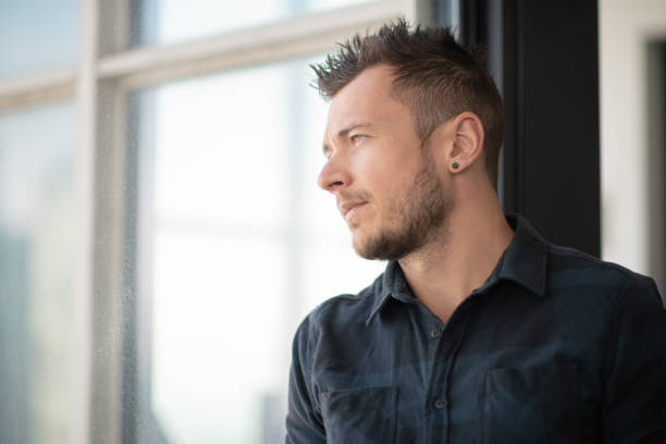 istock Portrait of contemplative man looking out window 1174259731