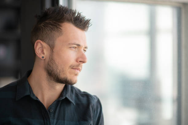 istock Portrait of contemplative man looking out window 1174259735