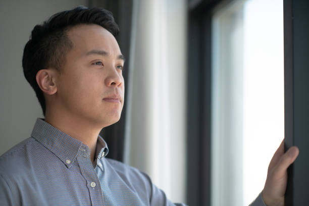 istock Portrait of thoughtful Chinese man looking out a window 1174259765
