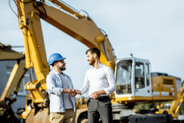 Builder with a sales consultant at the shop with heavy machinery Builder choosing heavy machinery for construction, talking with a sales consultant on the open ground of a shop with special vehicles construction machinery stock pictures, royalty-free photos & images