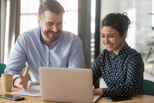 istock Multi-ethnic coworkers sitting at desk joking in the workplace 1174262733