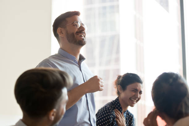Multi-ethnic corporate team laughing during briefing in office Multi-ethnic corporate team company staff laughing during briefing in modern office focus on business trainer executive coach european man in glasses joking having fun, teambuilding activities concept office buddies stock pictures, royalty-free photos & images