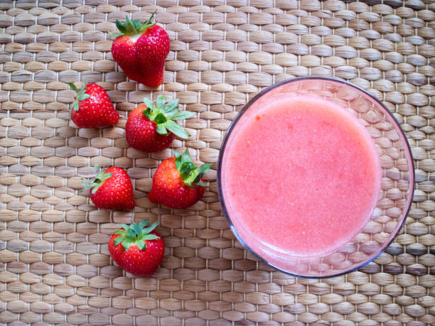 Strawberry smoothie with some strawberries as decoration on wicker background