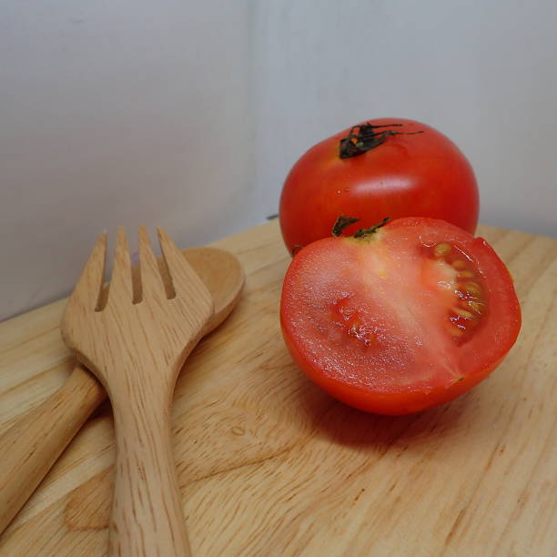 istock Two​ tomato on wood plate 1174274572