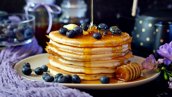 Breakfast pancake stack served with blueberries and honey.