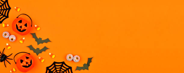 Halloween decor corner border banner over an orange background with copy space Halloween corner border banner with scattered candy and decor. Flat lay over an orange background with copy space. eye candy stock pictures, royalty-free photos & images
