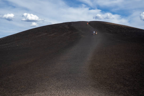 Hikers walk down from the Inferno Cone at Craters of the Moon National Monument stock photo