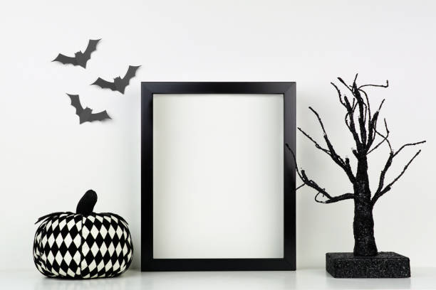 istock Mock up black frame with Halloween pumpkin and spooky tree decor on a shelf against a white wall 1174281514