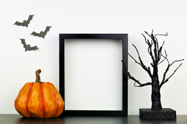 Mock up black frame with Halloween pumpkin and spooky tree decor on a shelf against a white wall Mock up black frame with pumpkin and spooky tree decor on a shelf or desk. Halloween concept. Portrait frame against a white wall with bats. pumpkin photos stock pictures, royalty-free photos & images