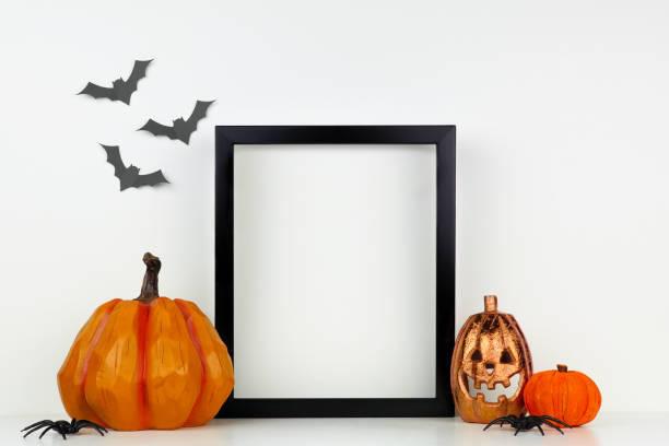 Mock up black frame with Halloween Jack o Lantern and pumpkin decor on a shelf against a white wall