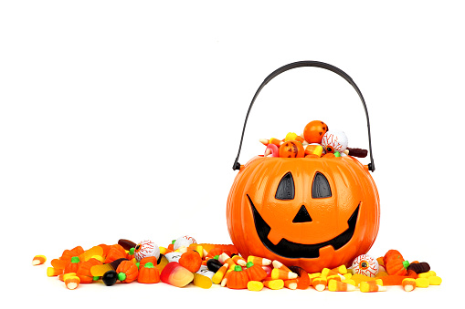 Cubo Jack o Lantern de Halloween lleno de caramelos aislados en blanco photo