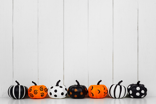 Calabazas de Halloween con patrones en una fila contra un fondo de madera blanca photo
