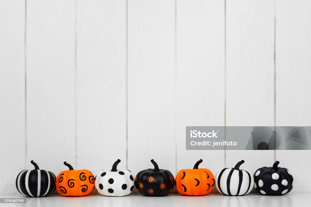 Patterned Halloween pumpkins in a row against a white wood background Black, white and orange patterned Halloween pumpkins in a row against a white wood background. Copy space. Halloween Stock Photo
