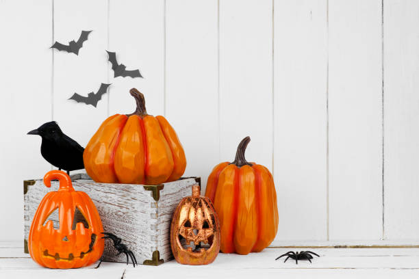 Halloween decor display with jack o lantern and pumpkins against white wood Halloween display with jack o lantern decor and pumpkins against a rustic white wood background. Copy space. halloween pumpkin decorations stock pictures, royalty-free photos & images