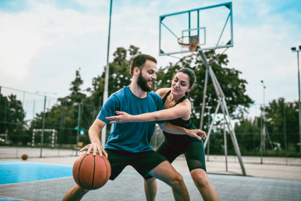Couple Enjoying Basketball Match Couple Enjoying Basketball Match asphalt basketball court stock pictures, royalty-free photos & images