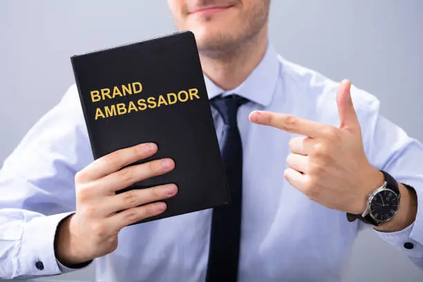 Photo of Man Holding Book With Brand Ambassador Text