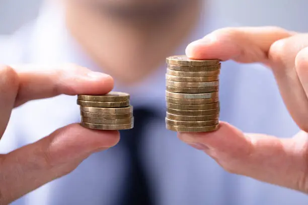 Photo of Man Comparing Two Coin Stacks