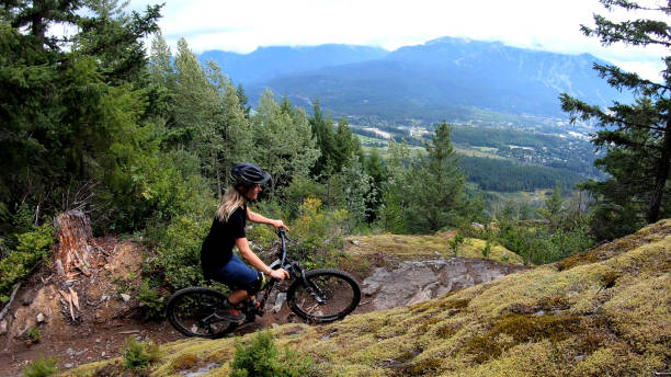 istock Female mountain biker rides on path through forest 1174298731