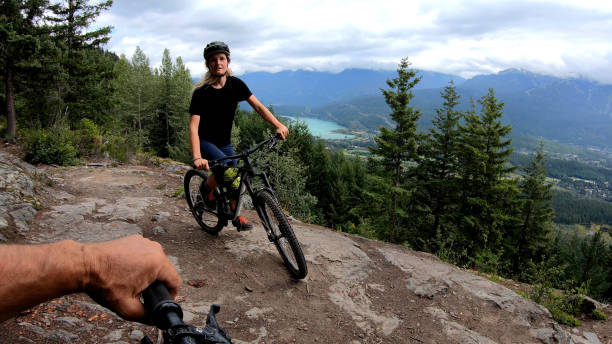 istock Female mountain biker rides on path through forest 1174298828