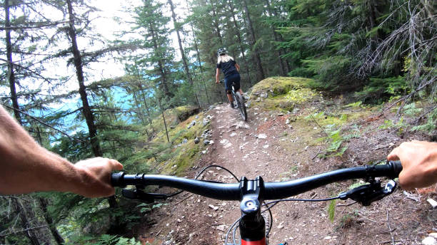 istock Female mountain biker rides on path through forest 1174299440