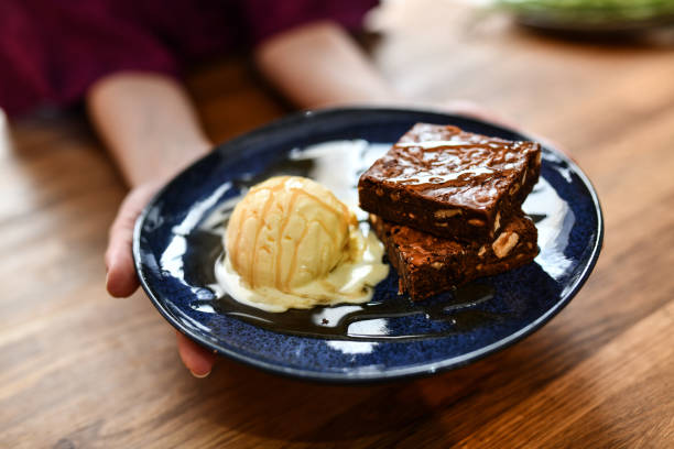 kobieta prezentująca pustynię brownie i lodów waniliowych - cookie chocolate cake gourmet dessert zdjęcia i obrazy z banku zdjęć