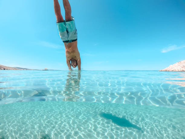 homme sautant dans la mer - spraying beaches summer sunlight photos et images de collection