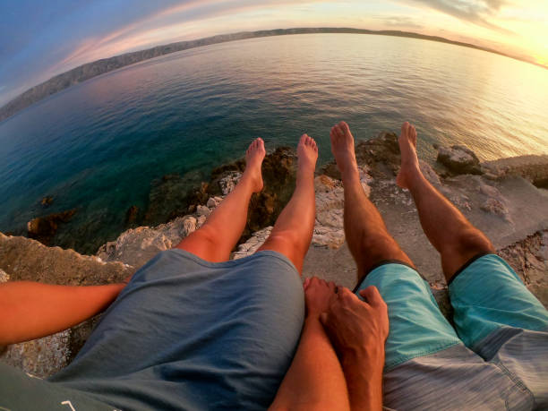 istock Couple sitting above sea at sunset 1174302142