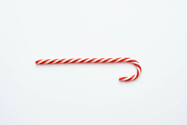 Festive Christmas treat. Flat lay of striped red candy cane isolated on white background. Copy space.