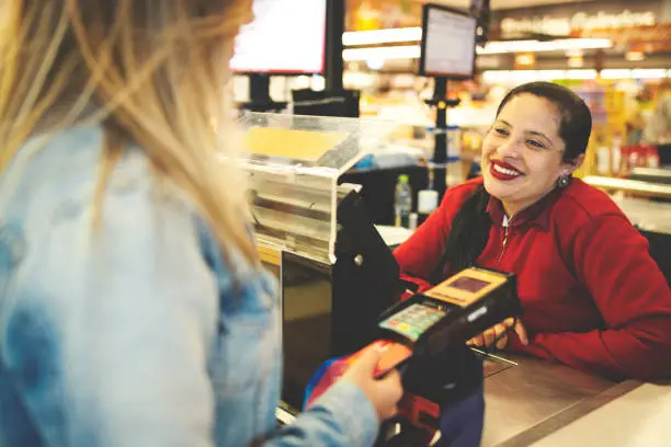 Photo of Modern woman paying purchases at supermarket checout using credit card