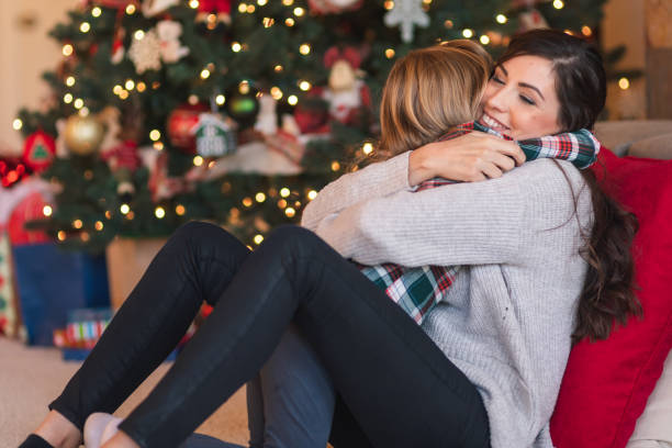 istock Mom snuggles with her daughter by the Christmas tree 1174331179