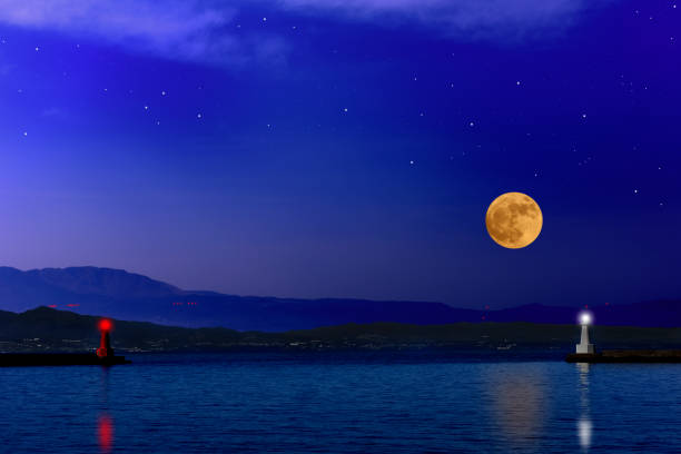 Full moon rising over the sea and the lighthouse with copy space.